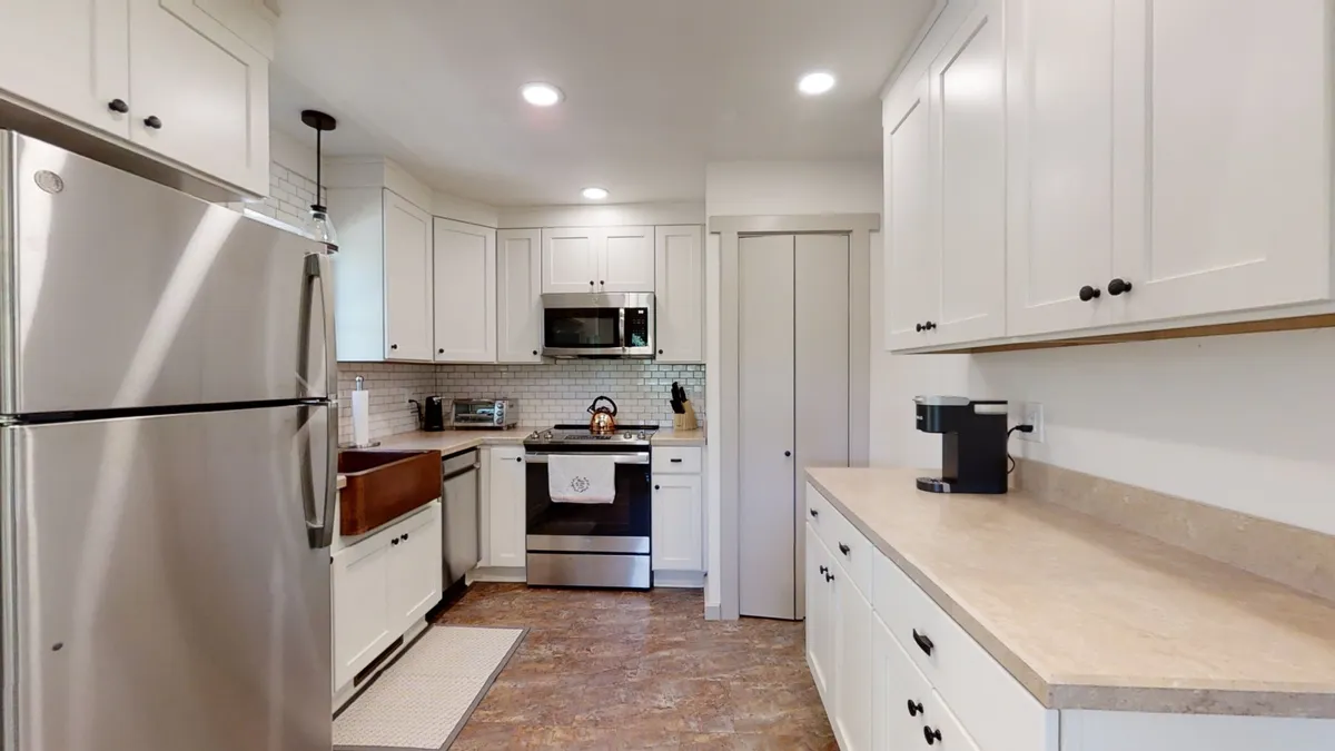 A bright, modern kitchen with white cabinetry and stainless steel appliances, designed for family gatherings and casual meals. The space feels open and welcoming—ideal for savoring coffee before hitting the trails or preparing snacks for a day of adventure.