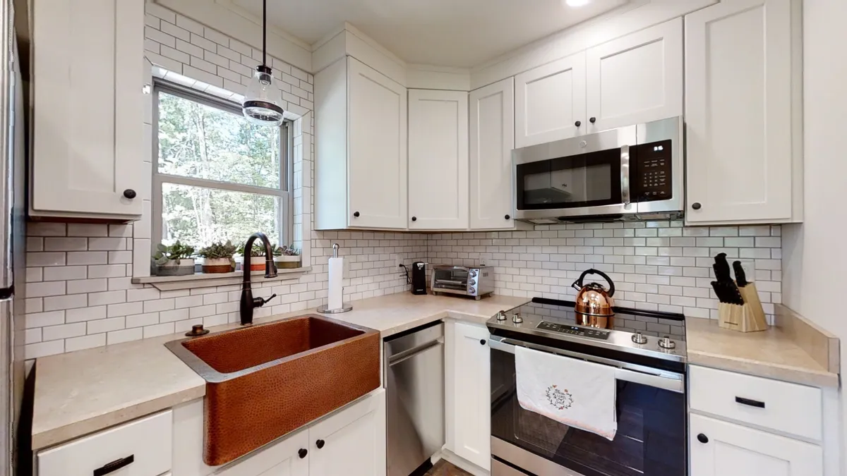 A beautifully appointed kitchen featuring a striking copper sink, stainless steel appliances, and warm wooden accents. The space is clearly designed for cooking and socializing, with thoughtful touches that invite homemade meals and communal gatherings.