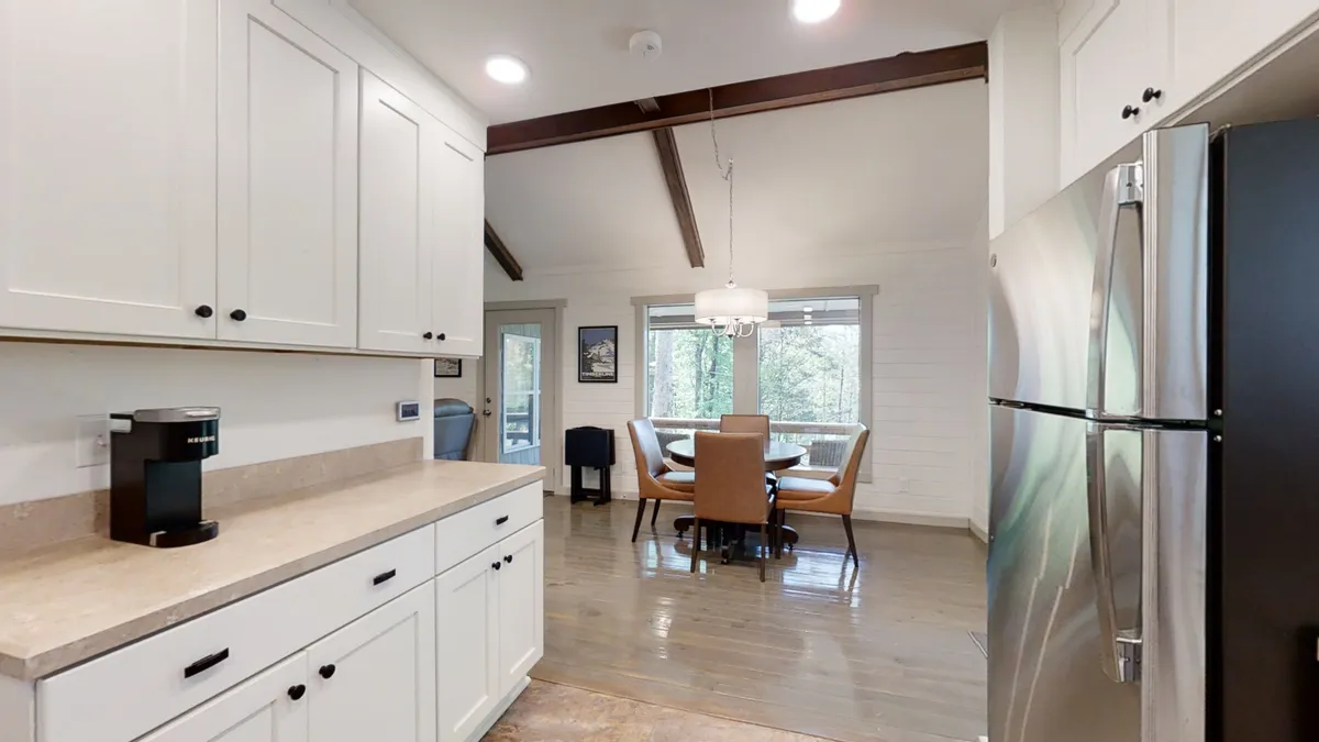 The image shows a bright kitchen and dining area, with a kitchen counter that opens onto a cozy dining space. The setup encourages family interaction and socializing, evoking the idea of preparing and enjoying meals together after outdoor adventures.